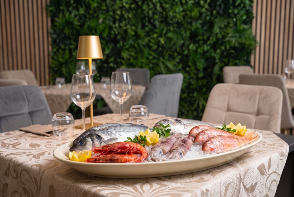 Pesce fresco selezionato: branzino, gamberi rossi, calamari e triglie su ghiaccio con limone