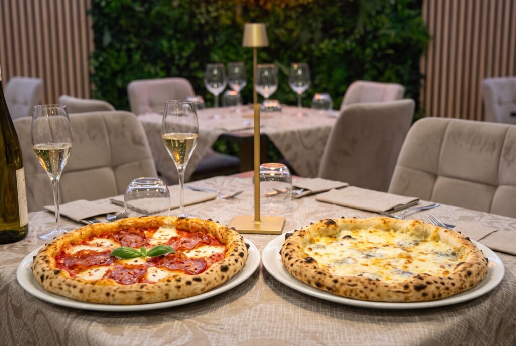 Pizza Diavola e pizza Quattro Formaggi su piatti bianchi al tavolo del ristorante