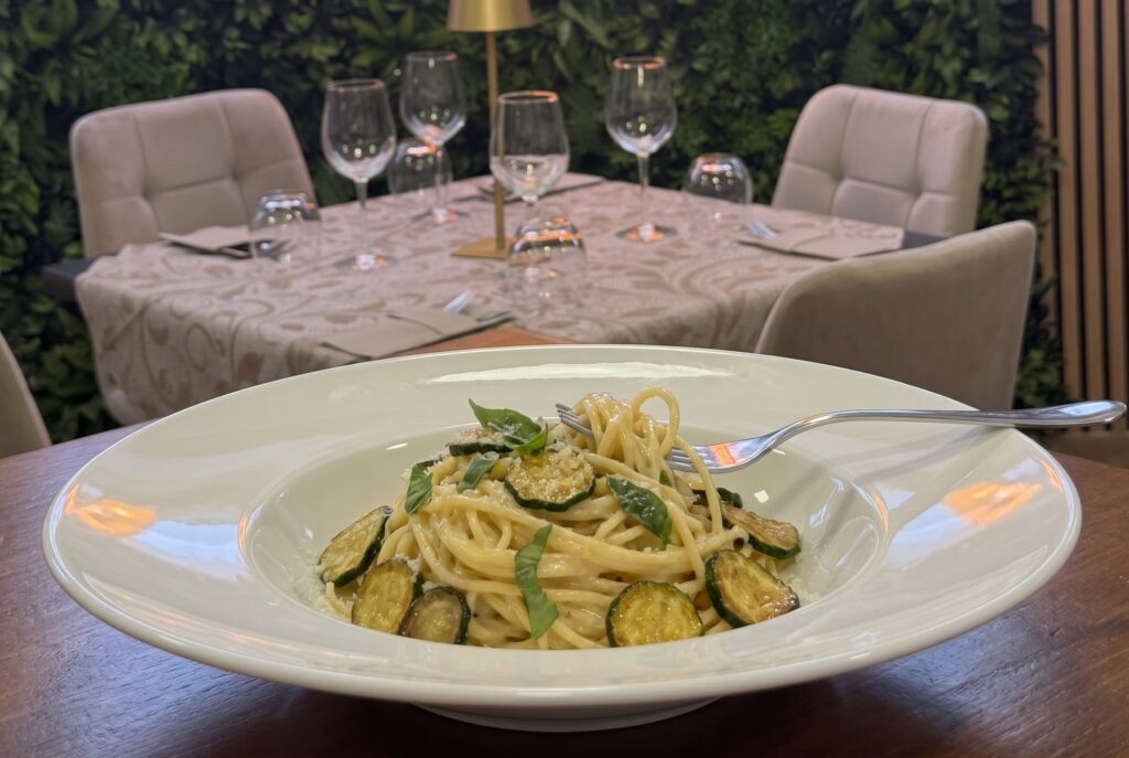 Spaghetti alla Nerano con zucchine dorate, provolone del Monaco e basilico in piatto bianco